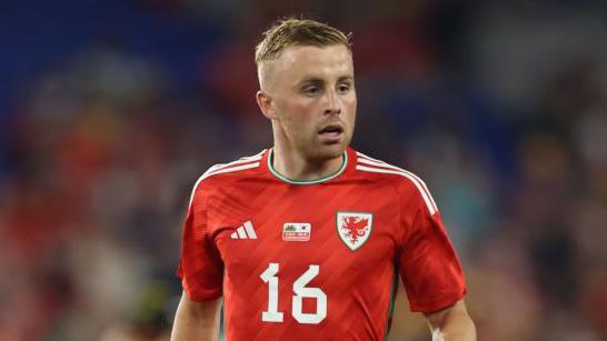 Joe Morrell looking to his left while running on the pitch during a match for Wales in 2023