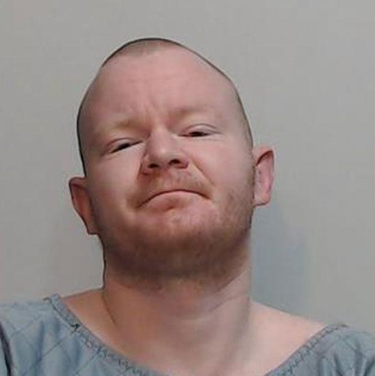A police picture of a man with short red hair and a slight growth of red beard