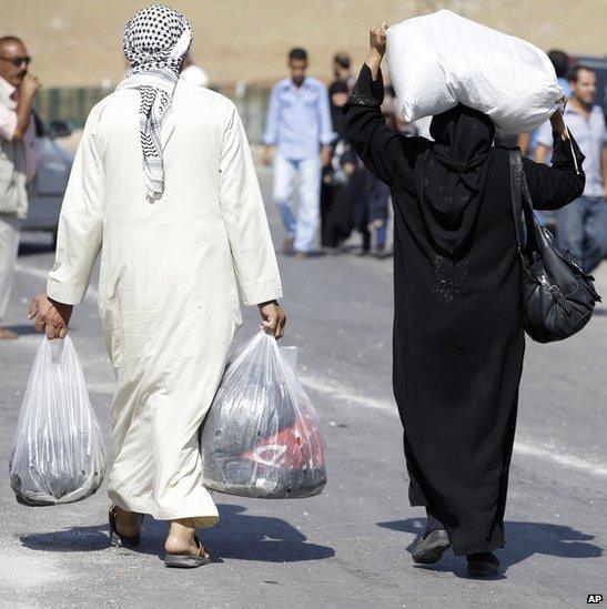 Syrian refugees carry their belongings after entering Turkish territory at the Cilvegozu border gate, in Turkey- 3 September 2013