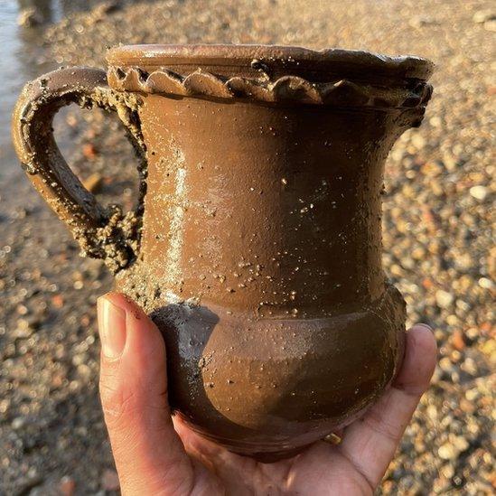 Image of Malcolm Russell's hand holding the brown sculpted drinking vessel.