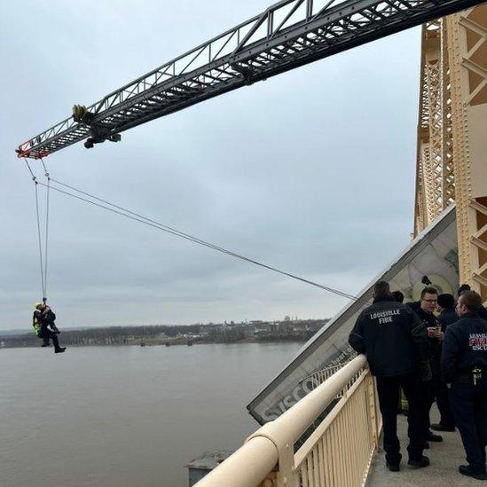 The rescue included a firefighter dangling from a ladder by a rope to access the truck