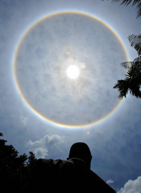 A rainbow circle in the sky, with the sun shining in the middle.