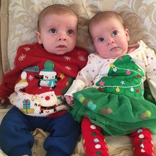 Two babies wearing Christmas jumpers