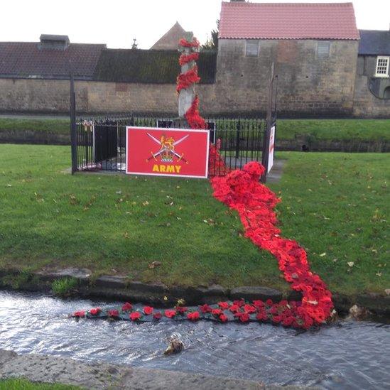 Cascading poppies from the war memorial into the stream