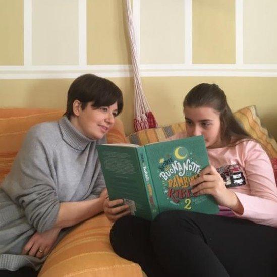 Daniela and her daughter Emma read together at home in Italy's red zone