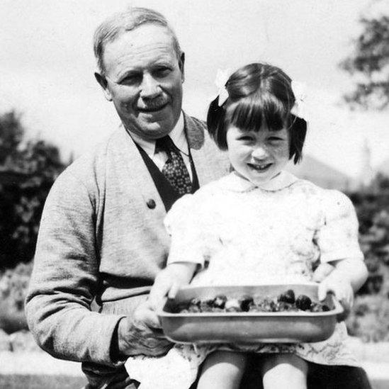 Doreen Black sitting on her grandfather David McKay Tulloch’s knee with strawberries