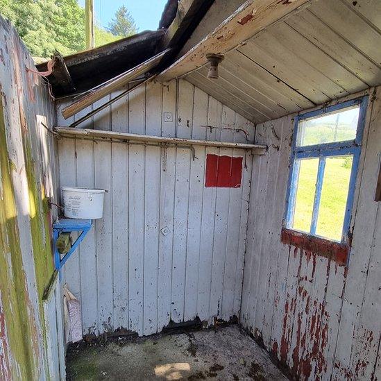 Interior view of the dilapidated hut shows the roof is open to the elements