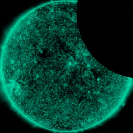 A green Sun with a round shadow across the top right-hand corner