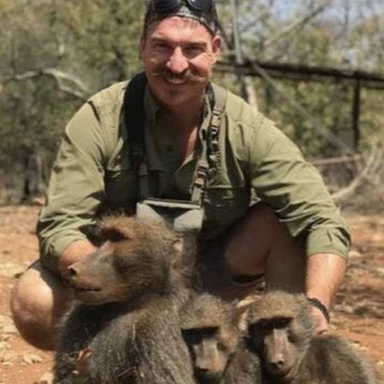 Fischer smiling, posing with dead baboons