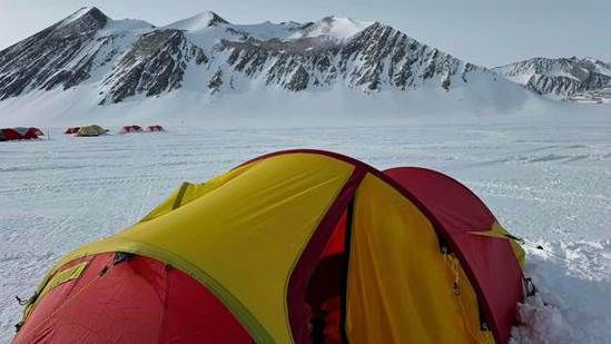 Mr Cox's red and yellow tent against the back drop of Antarctica in the snow 