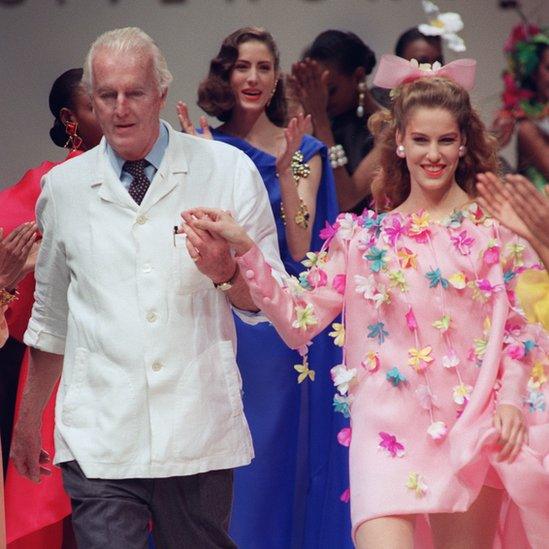 Hubert de Givenchy walks down catwalk with a model in floral Spring/Summer dress in 1991