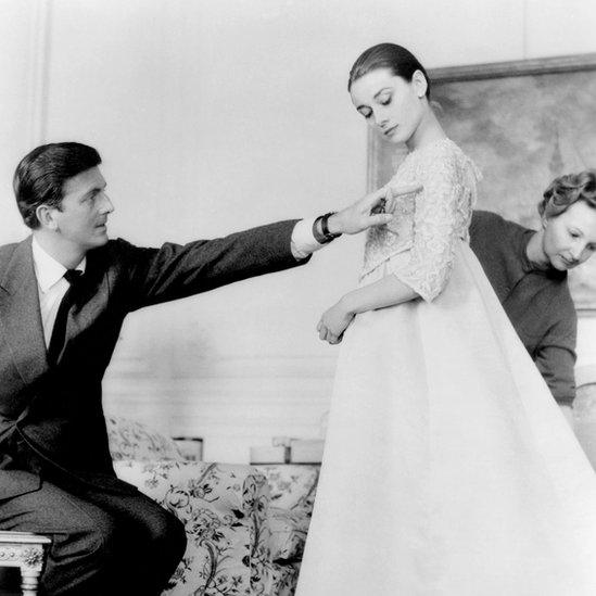 Givenchy and Audrey Hepburn in 1950s shot as she tries on a long-flowing, pale-coloured gown