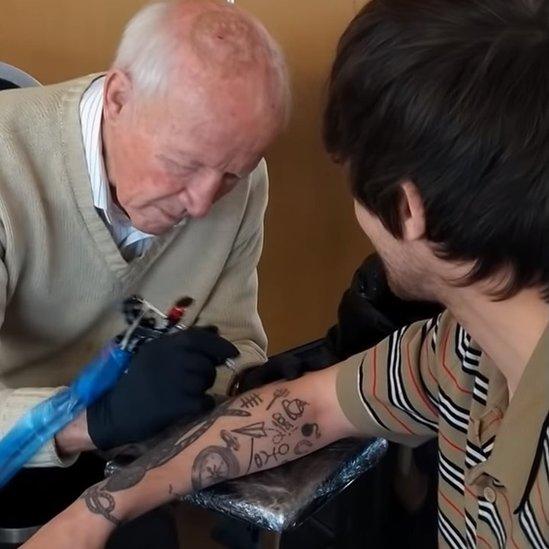 Richard giving Louis a tattoo