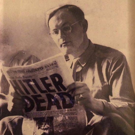 Jules Verhagen, a Dutch army repatriation officer at Dachau concentration camp, reading Stars and Stripes