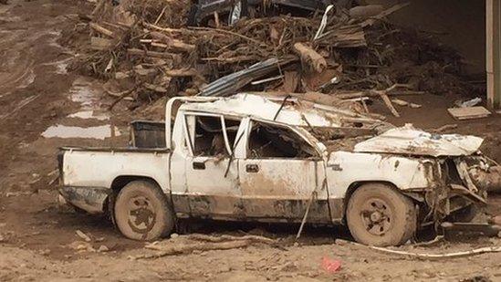 cars piled up, surround by debris, caused by the mudslide.