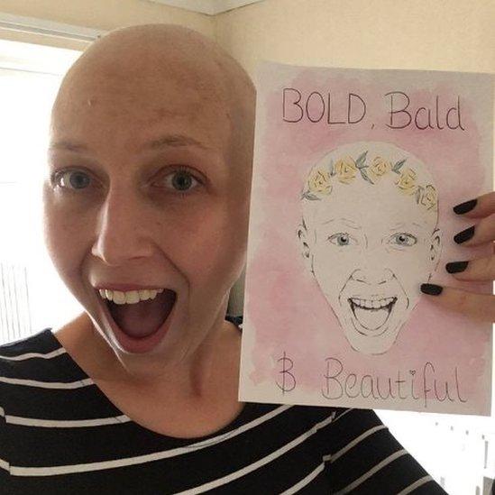 Kirsty Hopgood holding a 'bold, bald and beautiful' card