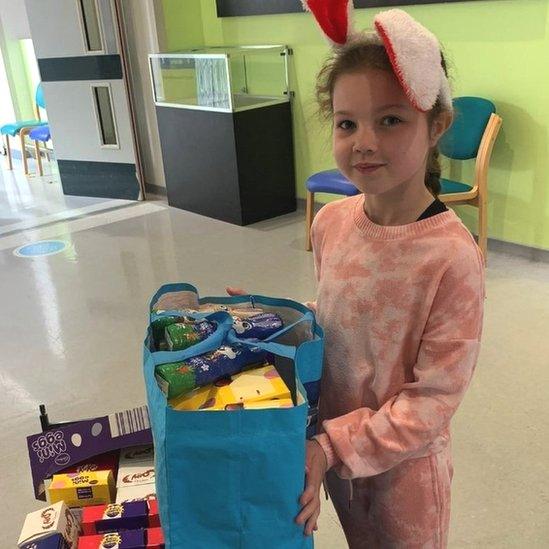 Ellie in a bunny outfit with a lot of Easter eggs in a hospital corridor