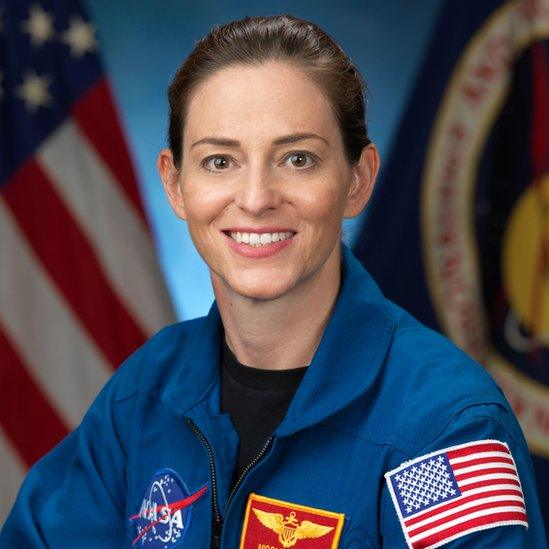 Nicole Mann poses for formal NASA photo in kit