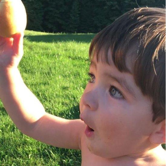 Rhys O'Neill's son gazing at a peach grown from the tree his dad bought for his mum on their first date