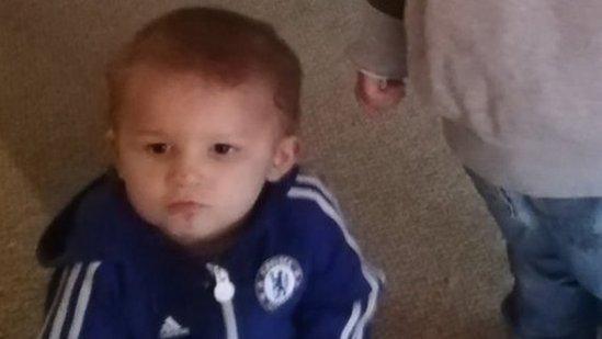 Image of Jacob Lennon sitting on the floor in a Chelsea FC tracksuit holding a cup.