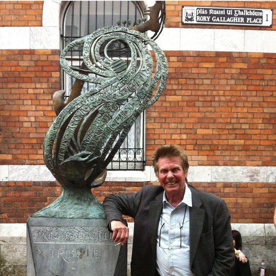 Irish musician Joe Brown poses beside Geraldine Creedon's sculpture at Rory Gallagher place in his hometown of Cork