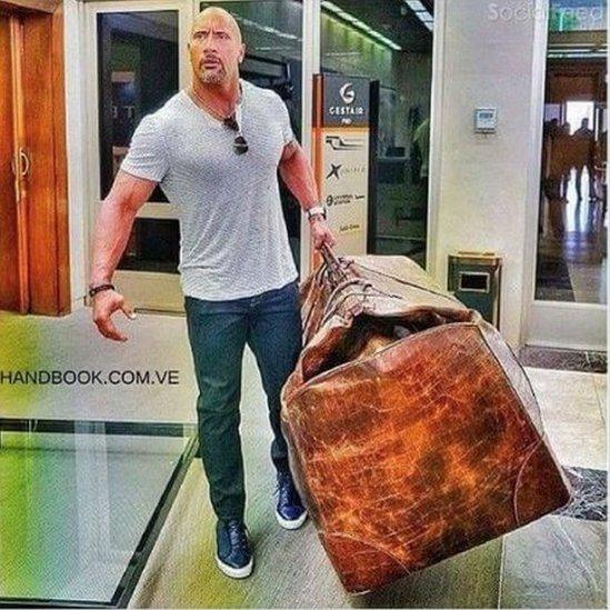 A photo of The Rock carrying an enormous suitcase