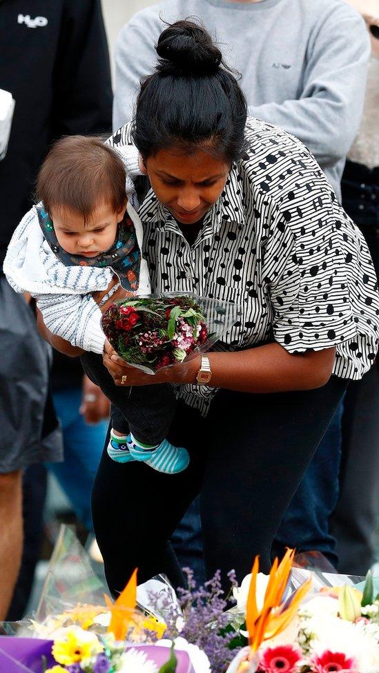 A woman lays flowers at the south side of London Bridge, close to Borough Market