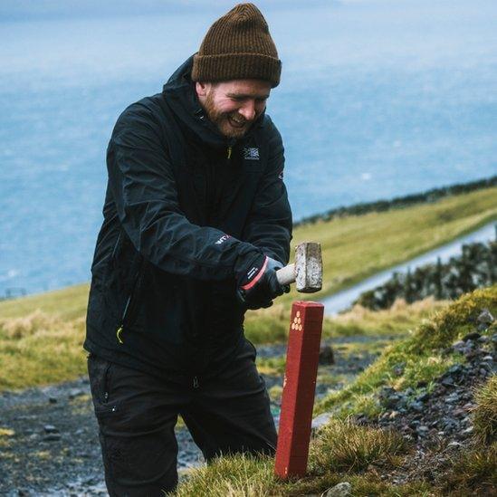 A Brown Team members hammers in a signpost