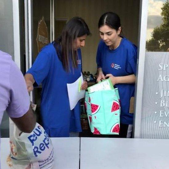 Volunteers hand out bags of food