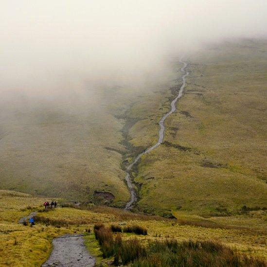 Walkers head into the clouds on the path towards Corn Du in the Brecon Beacons