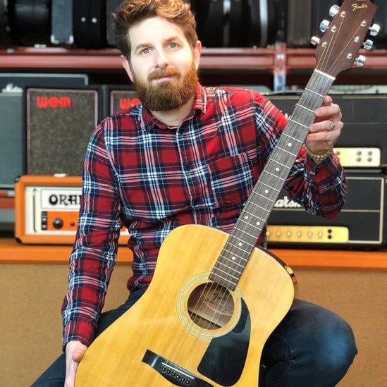 Auctioneer Luke Hobbs with the guitar, which the anonymous brothers bought from record producer Sylvia Massy last year