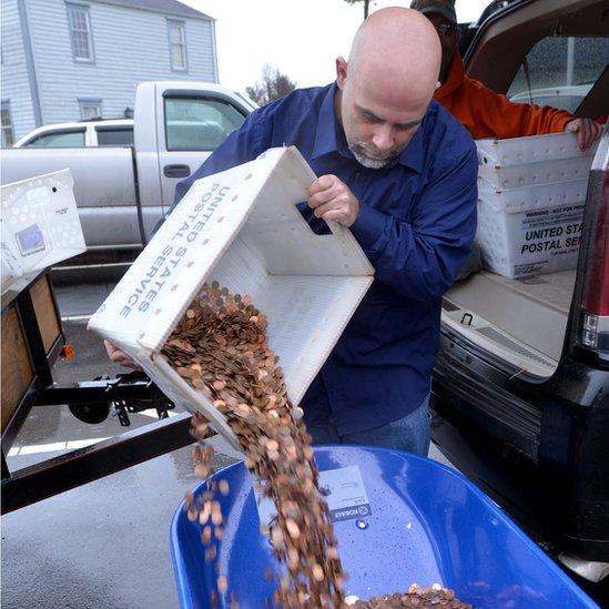 Nick Stafford pouring coins into a wheelbarrow (11 January 2017)