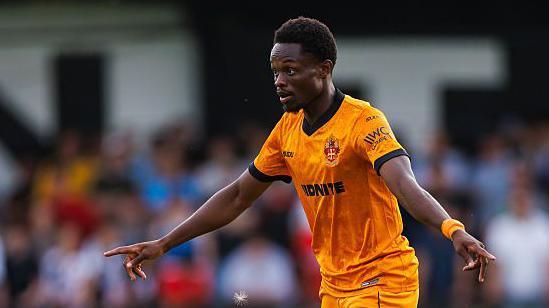Rafiki Said in action for Wolves in pre-season. He is wearing the club's old gold shirt and shorts and has both arms stretched out.
