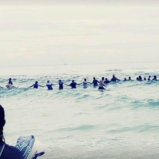 Image of people holding hands in the water to save drowning family