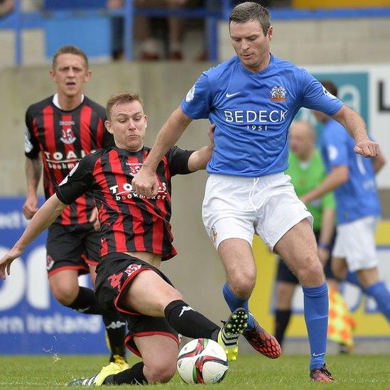 Andy Mitchell of Crusaders attempts to get to the ball before Glenavon opponent Kevin Braniff at Mourneview Park