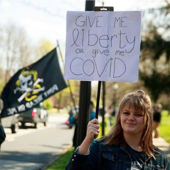 A protester holds a placard: "Give me liberty or give me Covid"