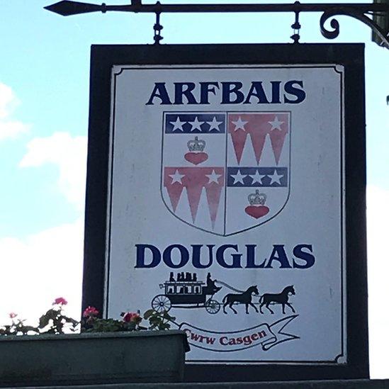 Arfbais teulu Douglas-Pennant ar arwydd y Douglas Arms heddiw