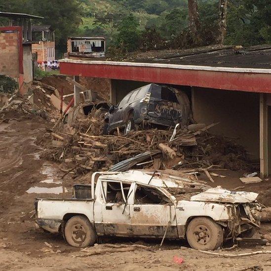 cars piled up, surround by debris, caused by the mudslide.