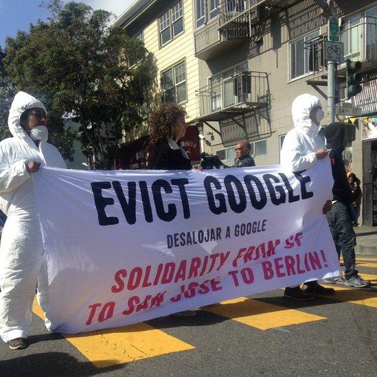 protesters hold "evict google" sign