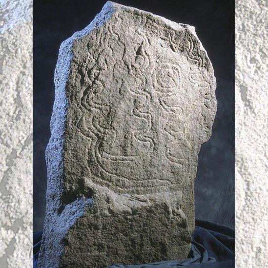 Standing stone decorated with carved zig-zag patterns on its surface