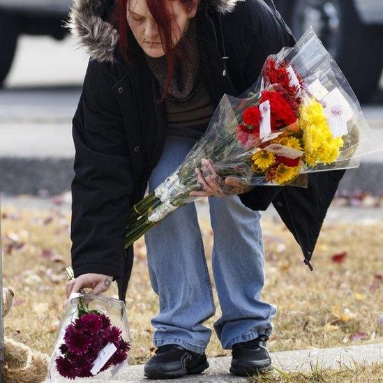 A mourner places flowers at a makeshift memorial at Woodmere Elementary (22 November 2016)