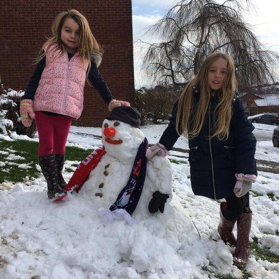 Alice and Sophie with their snowman wrapped in a Wales scraf