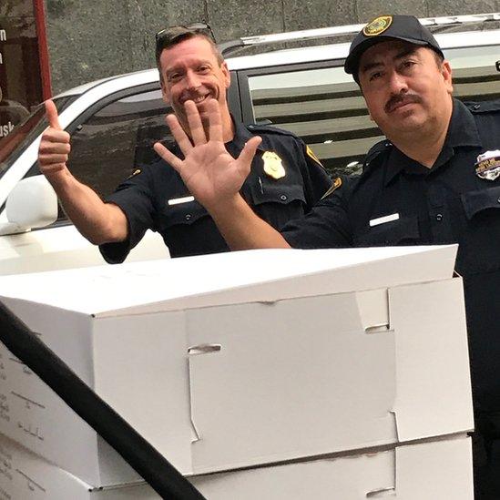 Two police officers unload boxes of bread