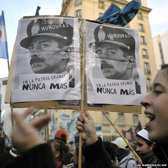 A demonstrator holds a placard with the portrait of Videla and the inscription "Honduras-Never Again In The Big Motherland" during a protest against the coup d'etat in Buenos Aires, on July 2, 2009.