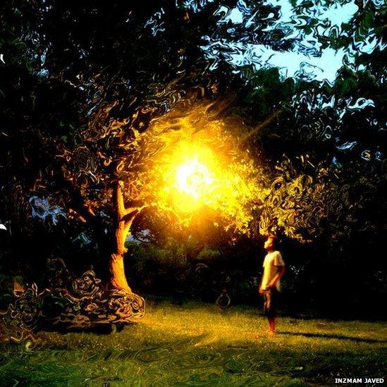 Image of man standing under light in dark garden