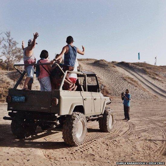 A man takes pictures of people in a Jeep