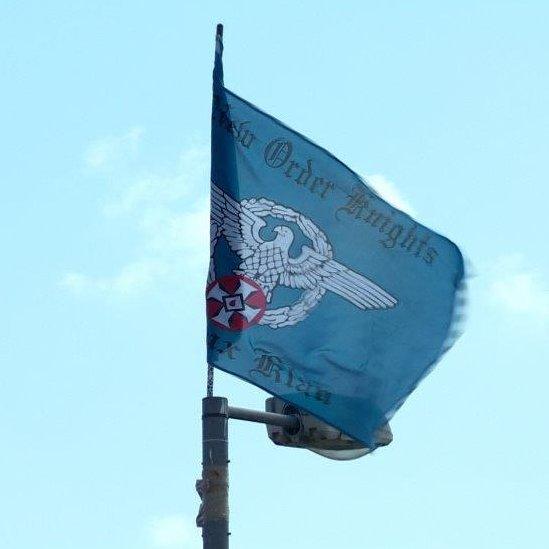 The flag bears the words New Order Knights and Ku Klux Klan