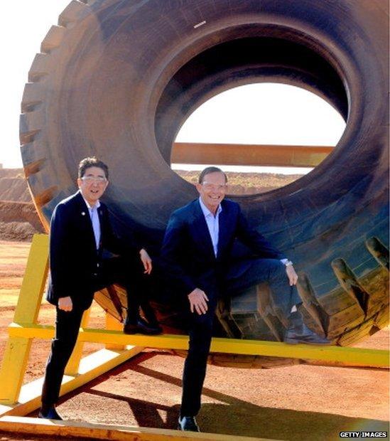 Prime Minister Tony Abbott (R) and Japanese Prime Minister Shinzo Abe pose for a photograph next to a haulage truck tyre during a tour of the Rio Tinto West Angelas iron ore mine in the Pilbara on 9 July 2014 in the Pilbara, West Australia