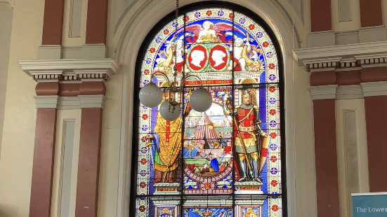 A large, colourful stained glass window in the former council chamber showing a depiction of St George 