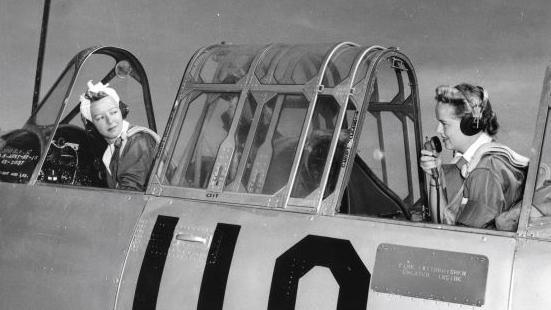 View of WASP (Women's Airforce Service Pilot) Leila Mather (left), in the pilot's seat of her plane, listens as WASP Martha Jane Thomas speaks on a radio microphone, Sweetwater, Texas, May 1943.